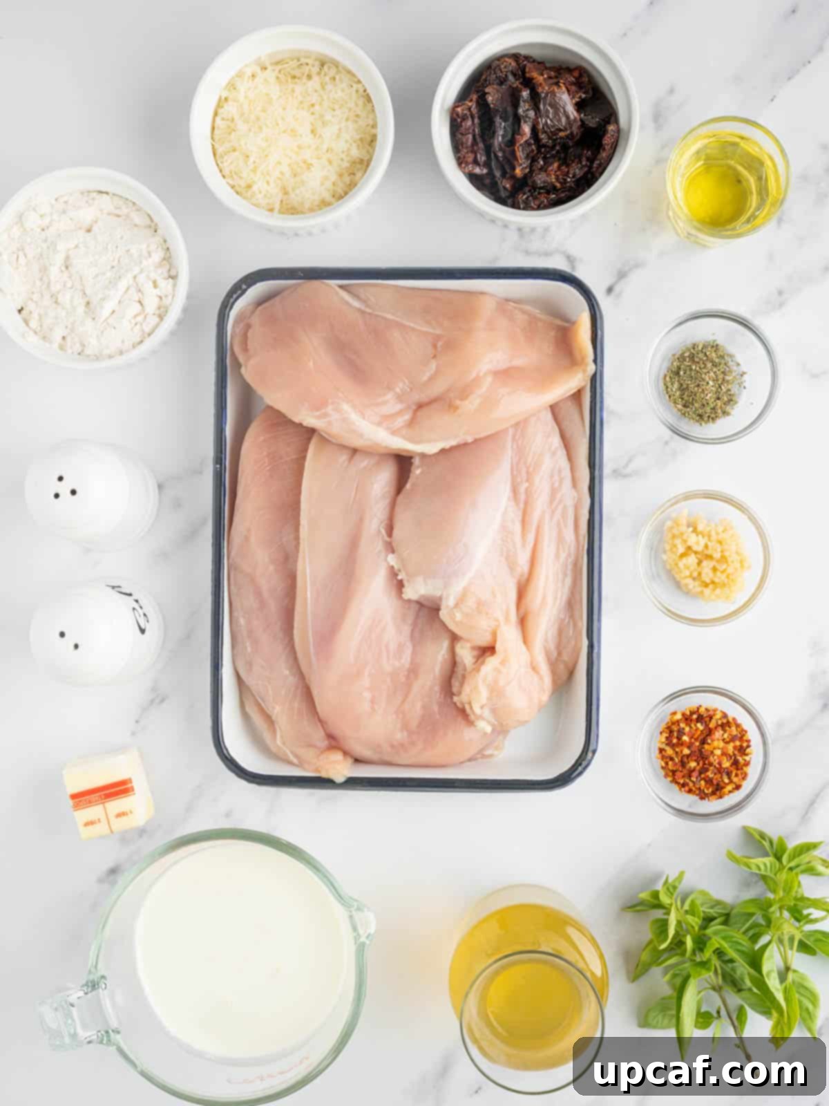 Effortless Marry Me Chicken Perfection 3 A flat lay of fresh ingredients laid out for an easy Marry Me Chicken recipe, including chicken breasts, garlic, sun-dried tomatoes, and cream.