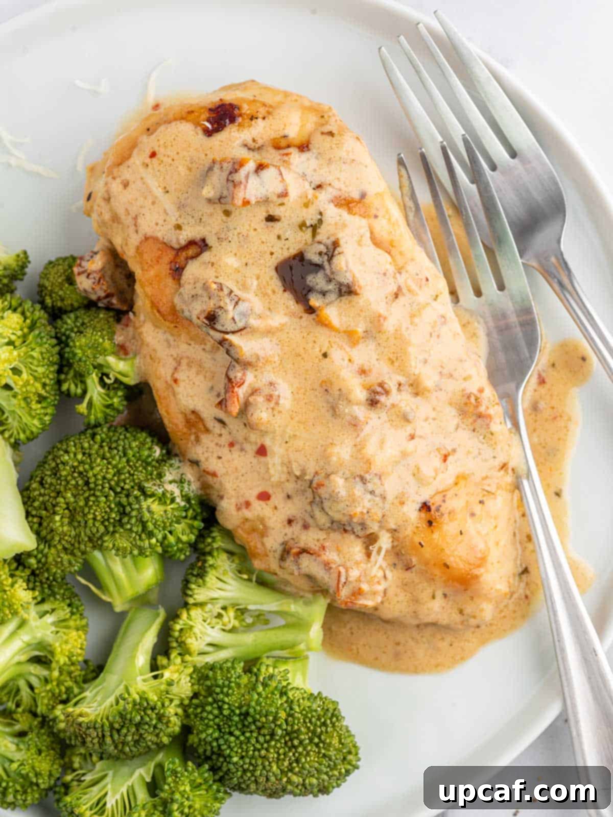 Effortless Marry Me Chicken Perfection 7 Creamy Marry Me Chicken recipe served on a white plate with steamed broccoli and a fork, ready to eat.