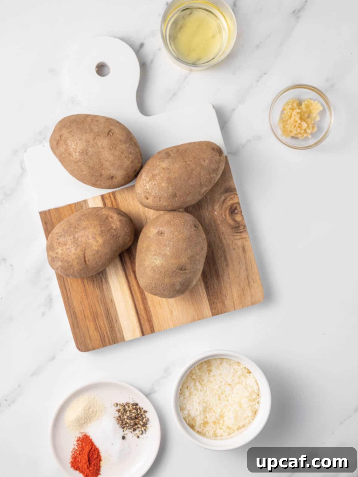 A vibrant display of fresh ingredients laid out for making air fryer potato wedges, including russet potatoes, garlic, olive oil, and various spices.