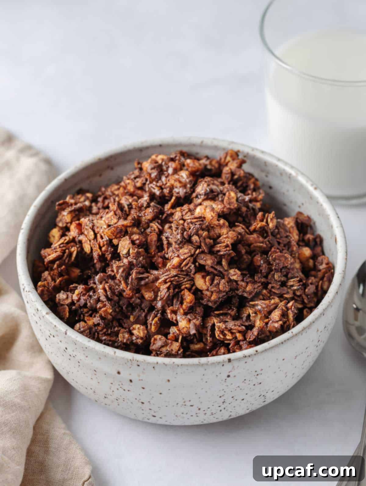 A inviting bowl of homemade chocolate granola with a glass of milk beside it, ready for a healthy breakfast or snack.