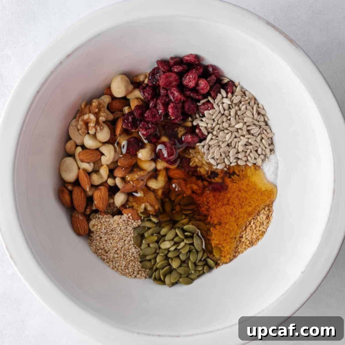Nuts and seeds combined with honey mixture in a bowl.