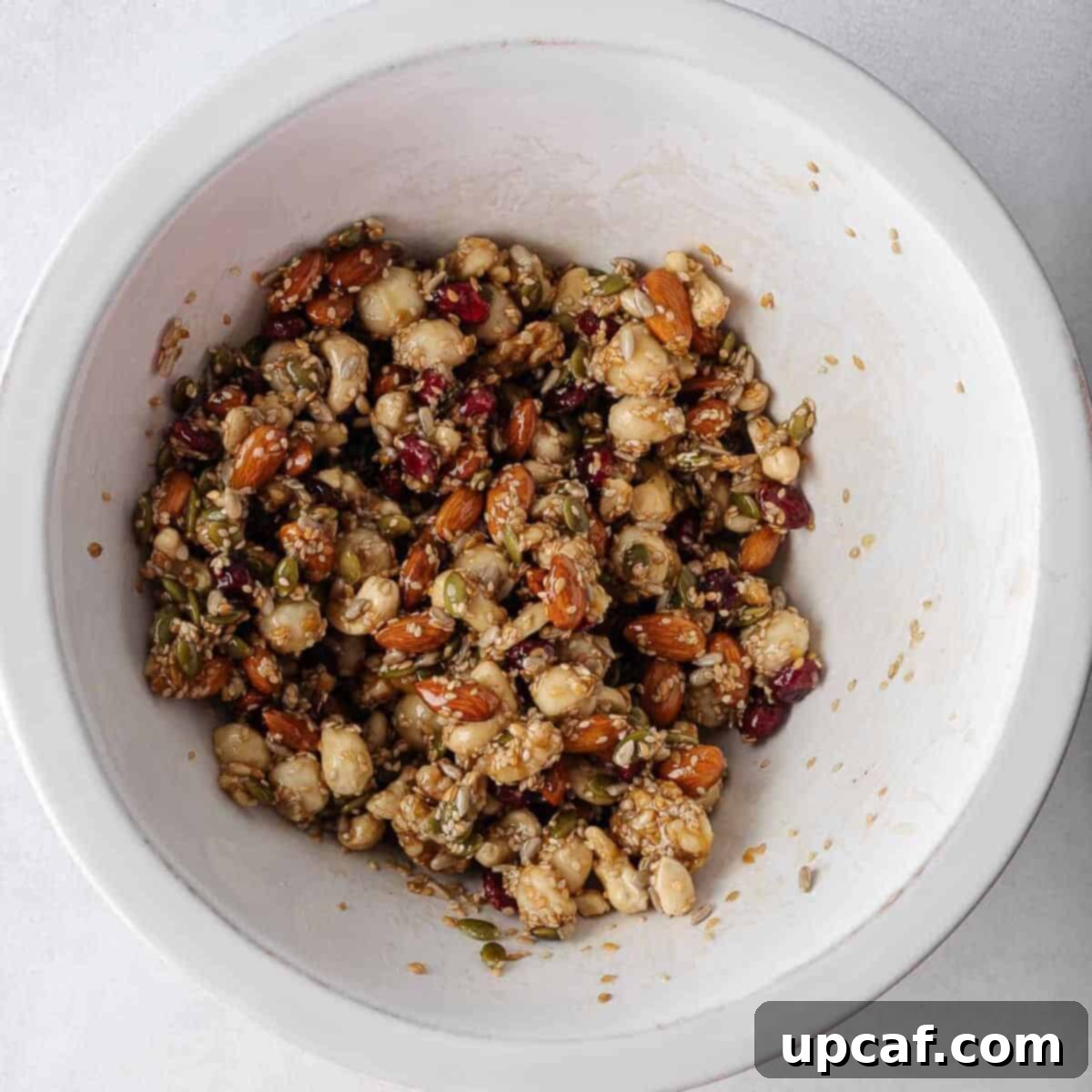 Nuts and seeds combined with honey mixture in a bowl.
