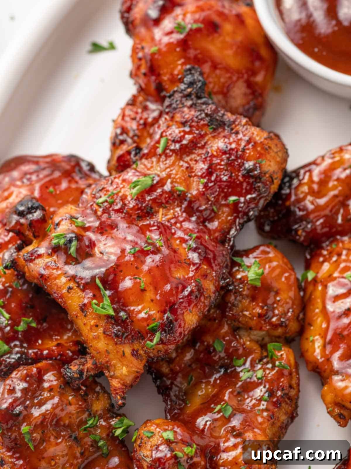 Closeup of air fryer barbecue chicken thighs with charred barbecue sauce.