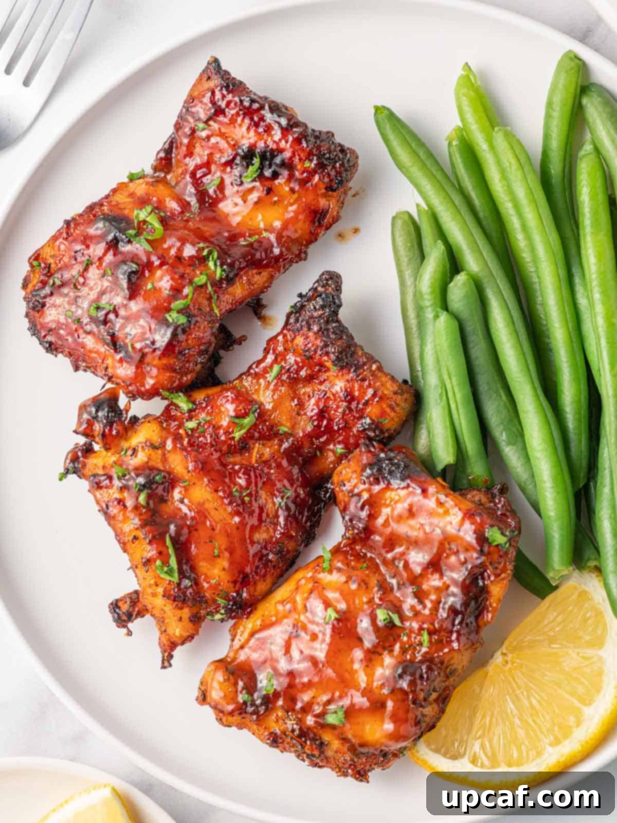 Best air fryer chicken thighs on a plate with green beans as a side.