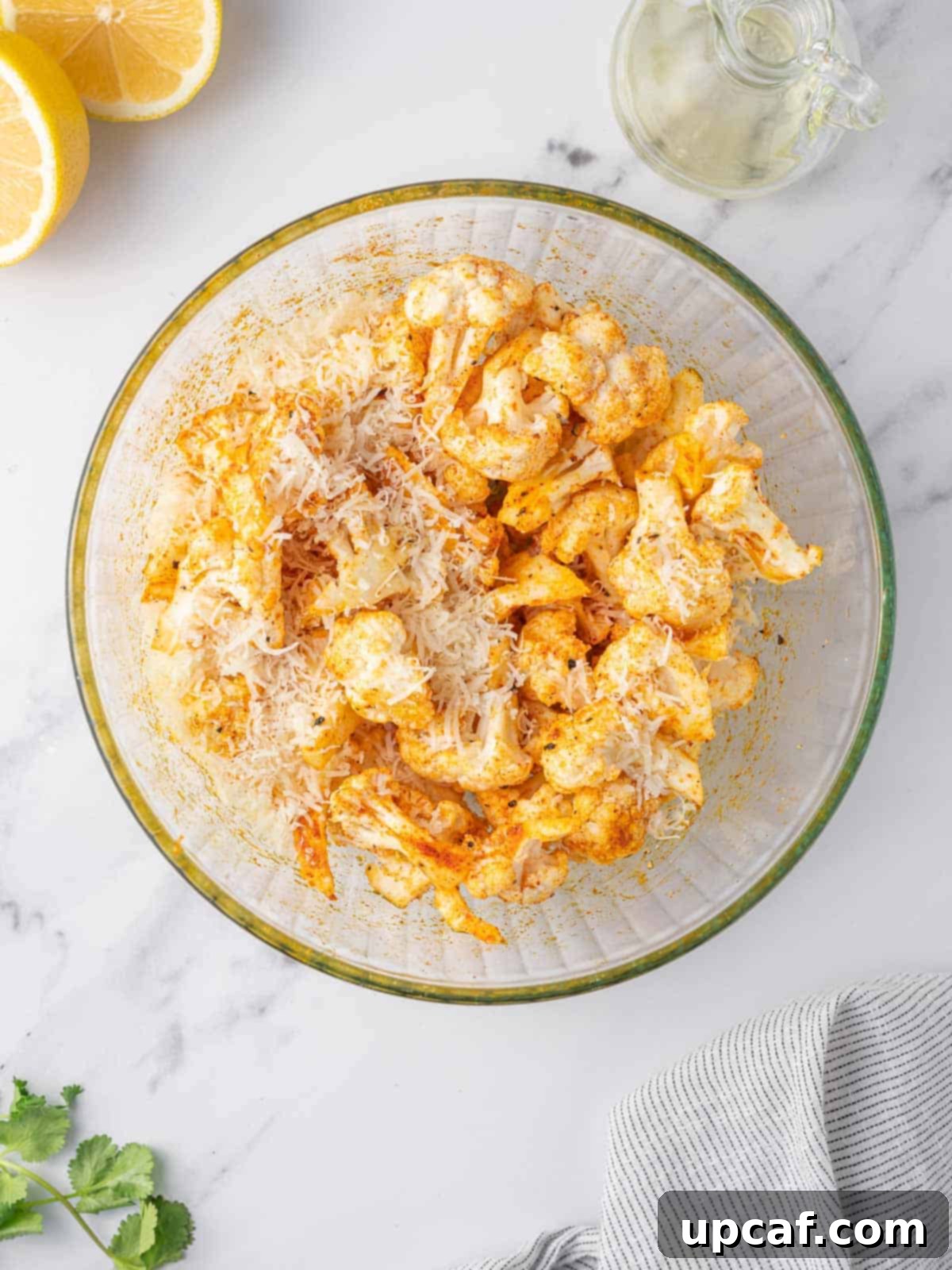 Cauliflower florets being tossed with a vibrant spice mix in a bowl, illustrating the seasoning process.