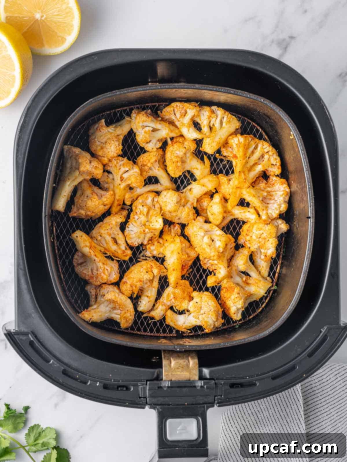 Seasoned and oiled cauliflower florets resting in a bowl, ready to be transferred to the air fryer.
