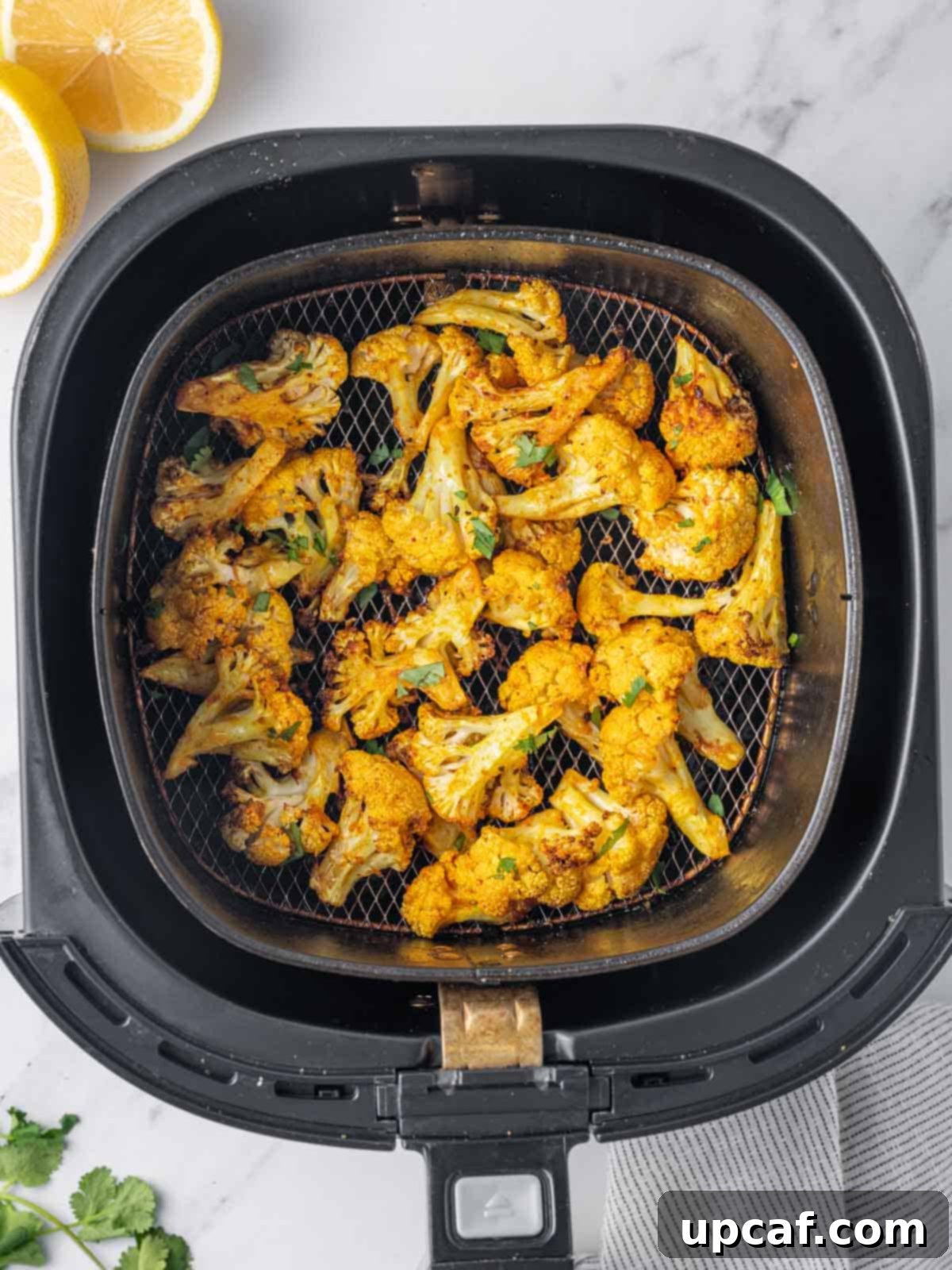 Freshly air-fried cauliflower bites in the air fryer basket, showing their golden brown, crispy texture.