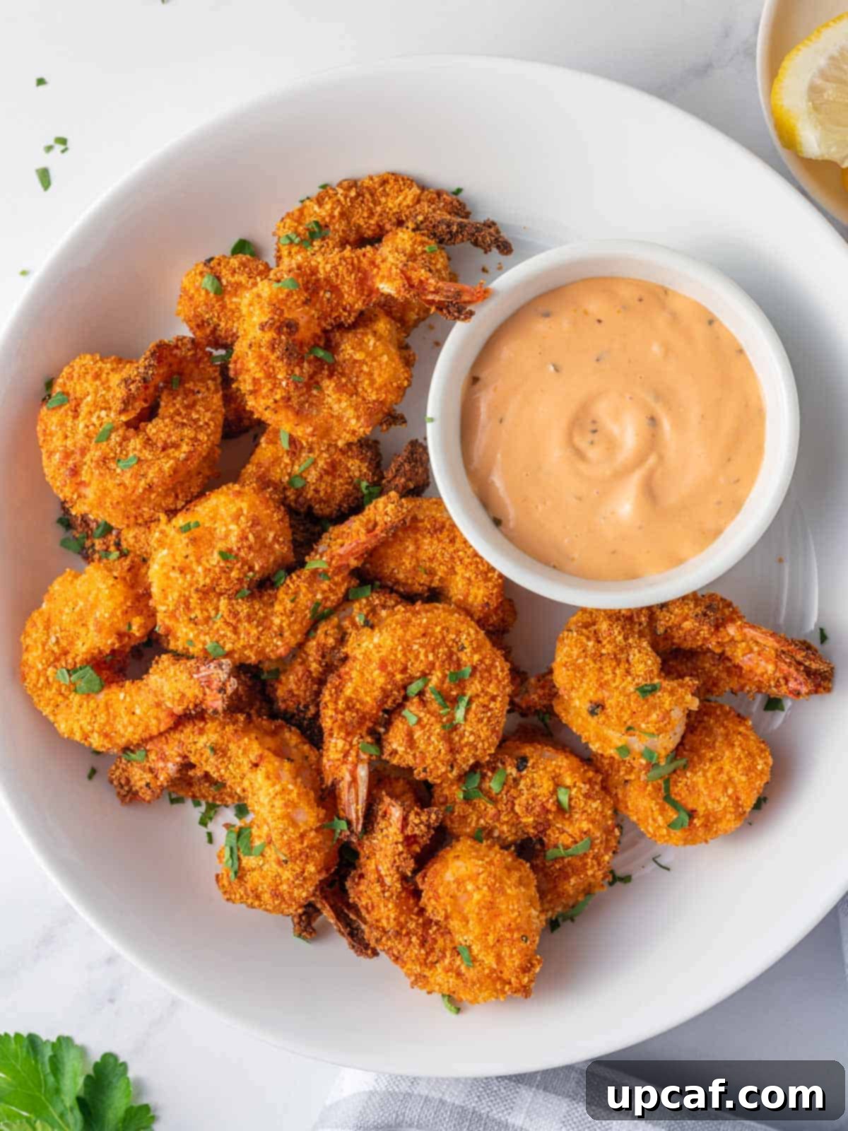 A platter of crunchy keto breaded shrimp and a bowl of dipping sauce.