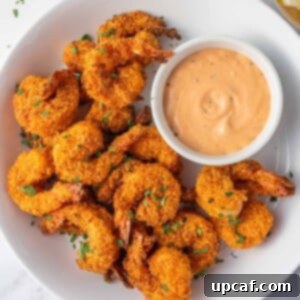 A platter of crunchy keto breaded shrimp and a bowl of dipping sauce.