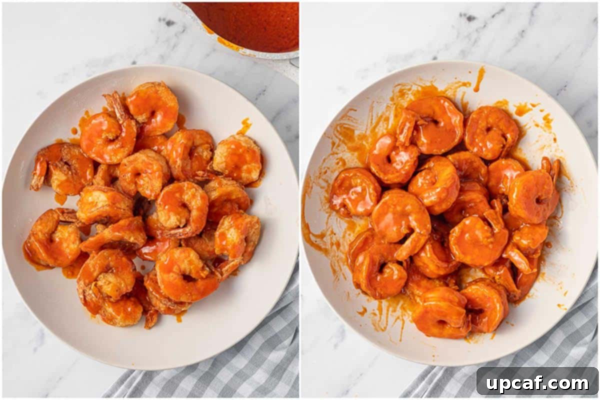 Fried shrimp being tossed in a bowl with buffalo sauce to evenly coat them.