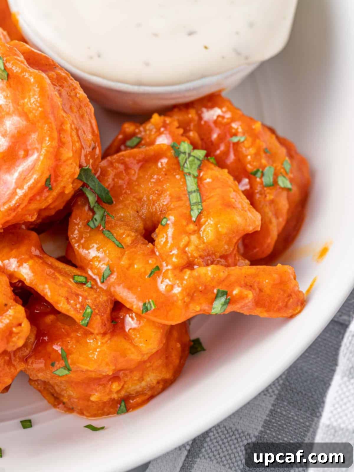 A close-up shot of several buffalo shrimp on a plate, showing their crispy coating and vibrant sauce.
