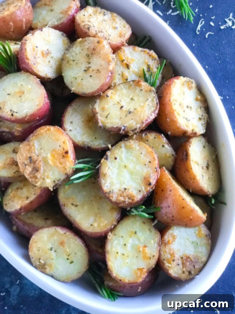 Parmesan roasted potatoes served in a white dish, garnished with fresh herbs, showcasing their golden-brown crispy exterior.