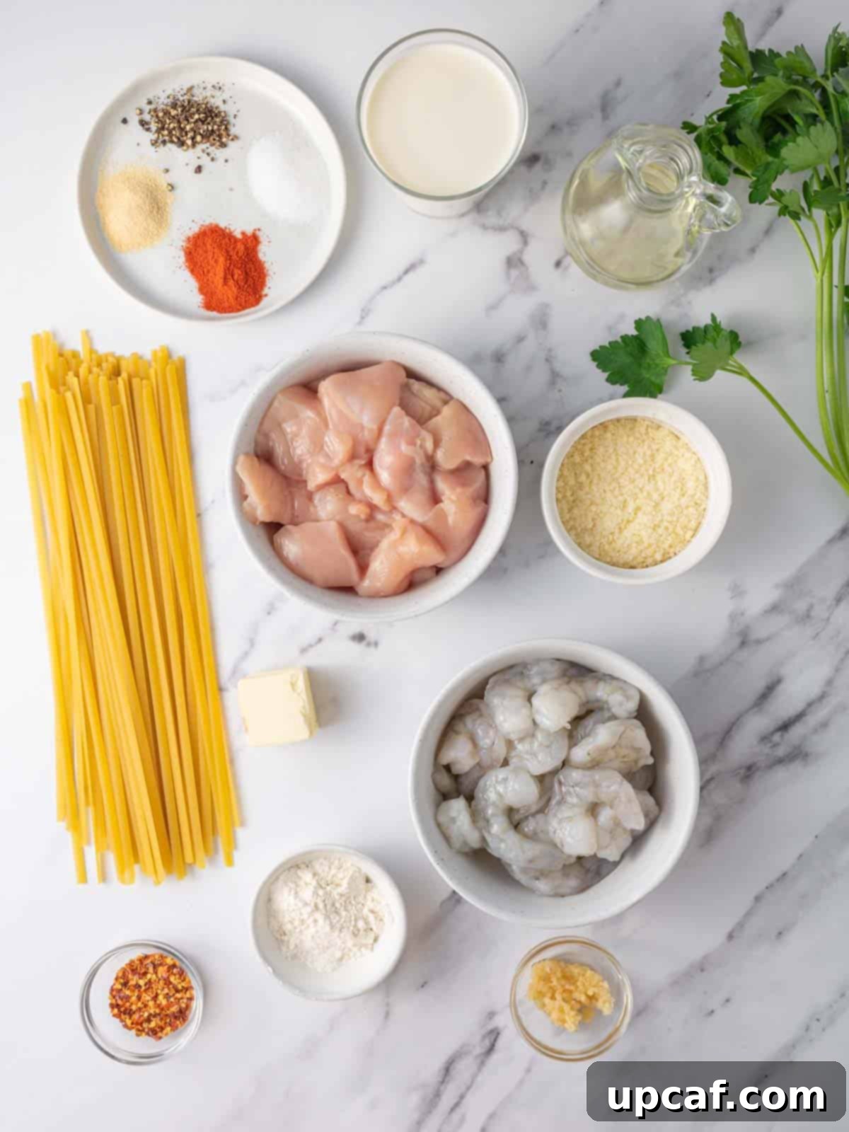 A selection of fresh ingredients laid out for chicken and shrimp alfredo.