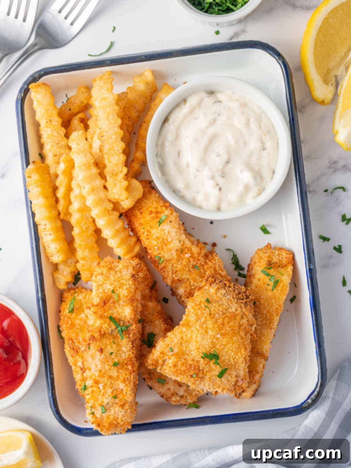 Guilt-Free Crispy Air Fryer Fish and Chips 6 A plate of perfectly cooked air fryer fish and chips with a side of tartar sauce and lemon.
