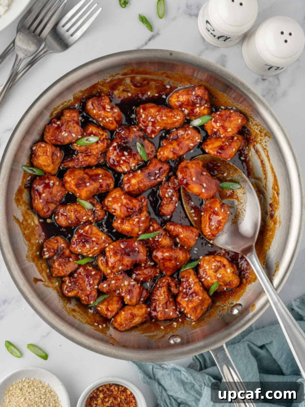 A spoon scoops gochujang sauce of crispy chicken.