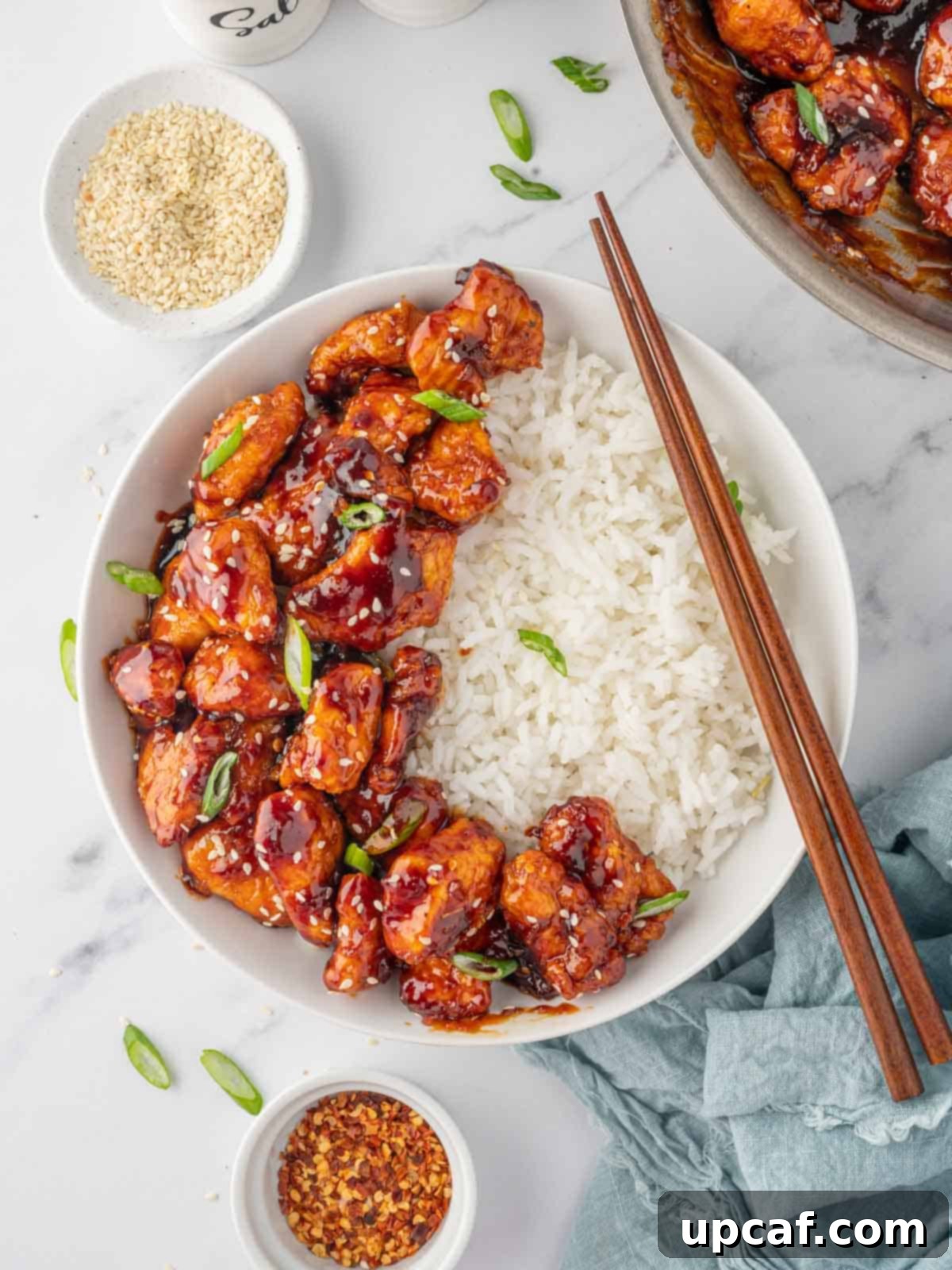 Crispy gochujang chicken bites over a bed of rice with chopsticks.