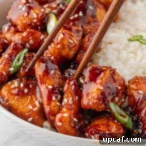 Chopsticks pick up a chicken in gochujang sauce.
