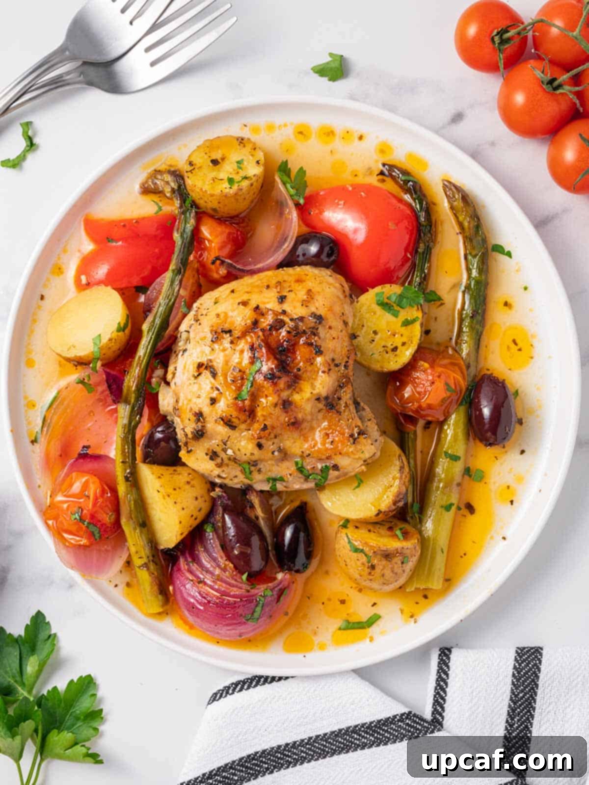A plate of Mediterranean chicken with roasted vegetables and olives.
