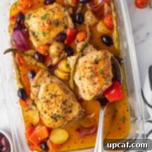 A spoon picks up a juicy chicken thigh from a baked dish.