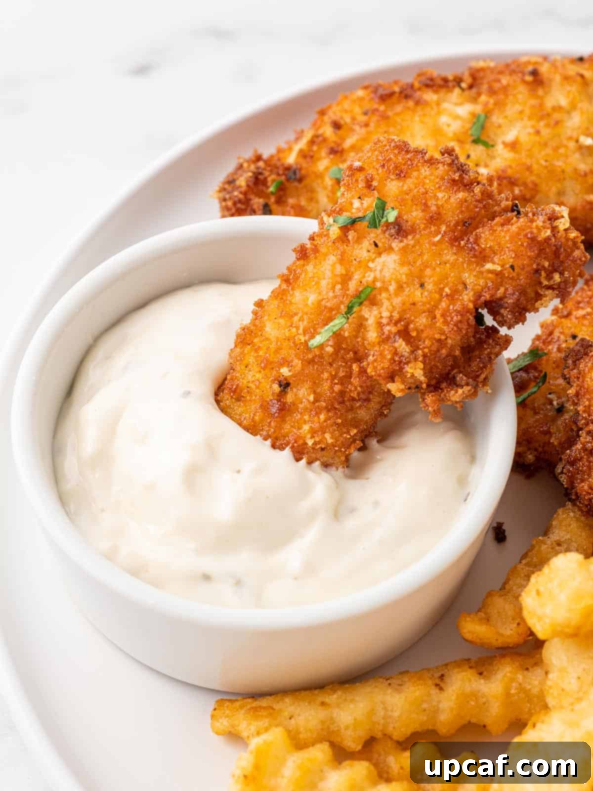 Panko crusted cod is dipped into tarter sauce.