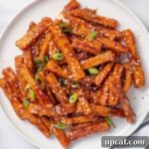 Spicy Honey Glazed Potatoes 11 A plate of chilli fries topped with sesame seeds and green onions.