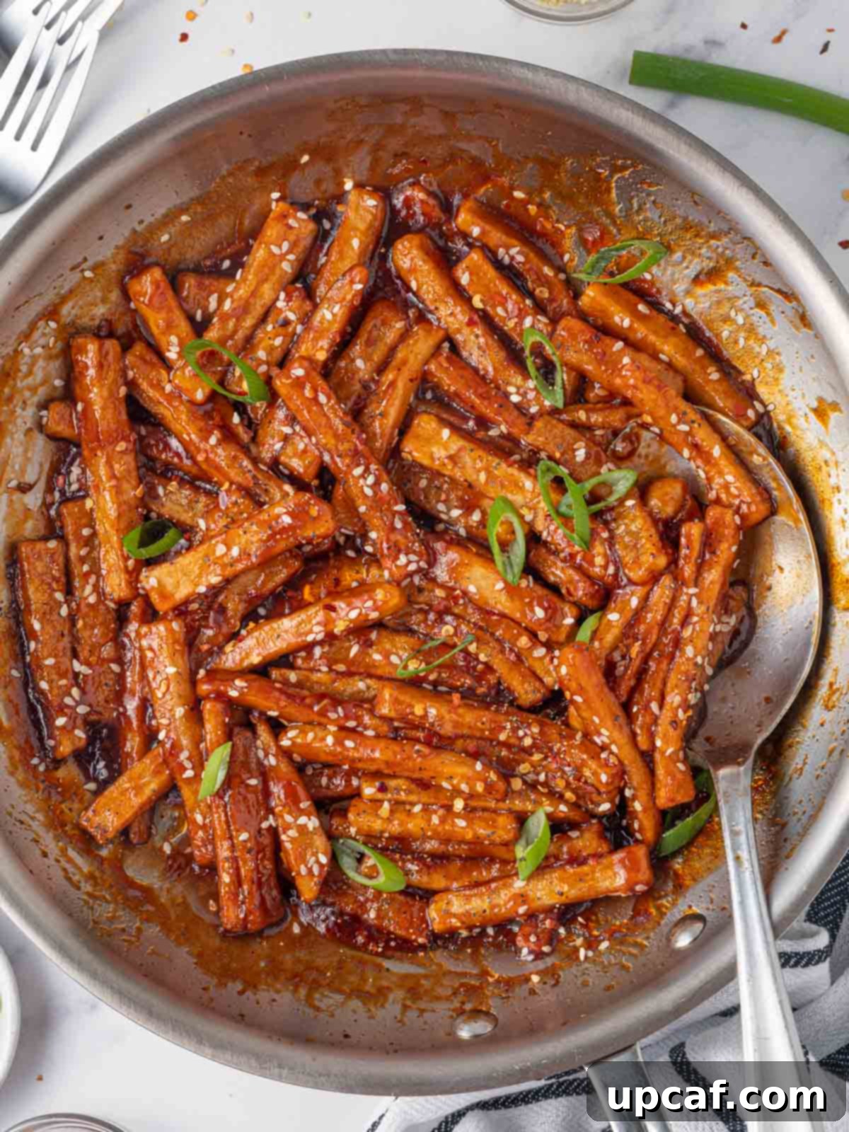 Spicy Honey Glazed Potatoes 8 A skillet of sweet chilli potatoes with a spoon.