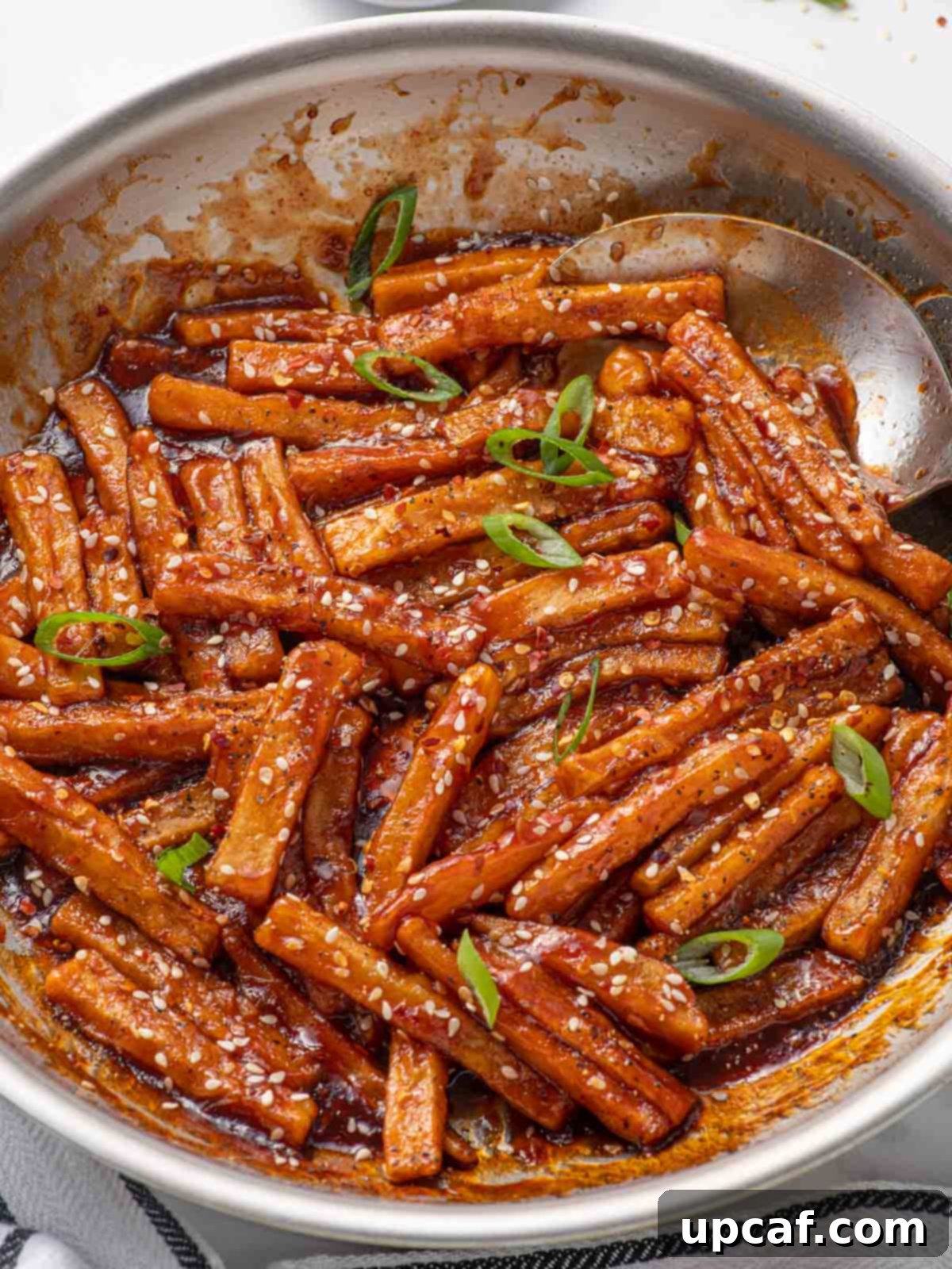 Spicy Honey Glazed Potatoes 9 A spoon coats potatoes with chilli sauce.