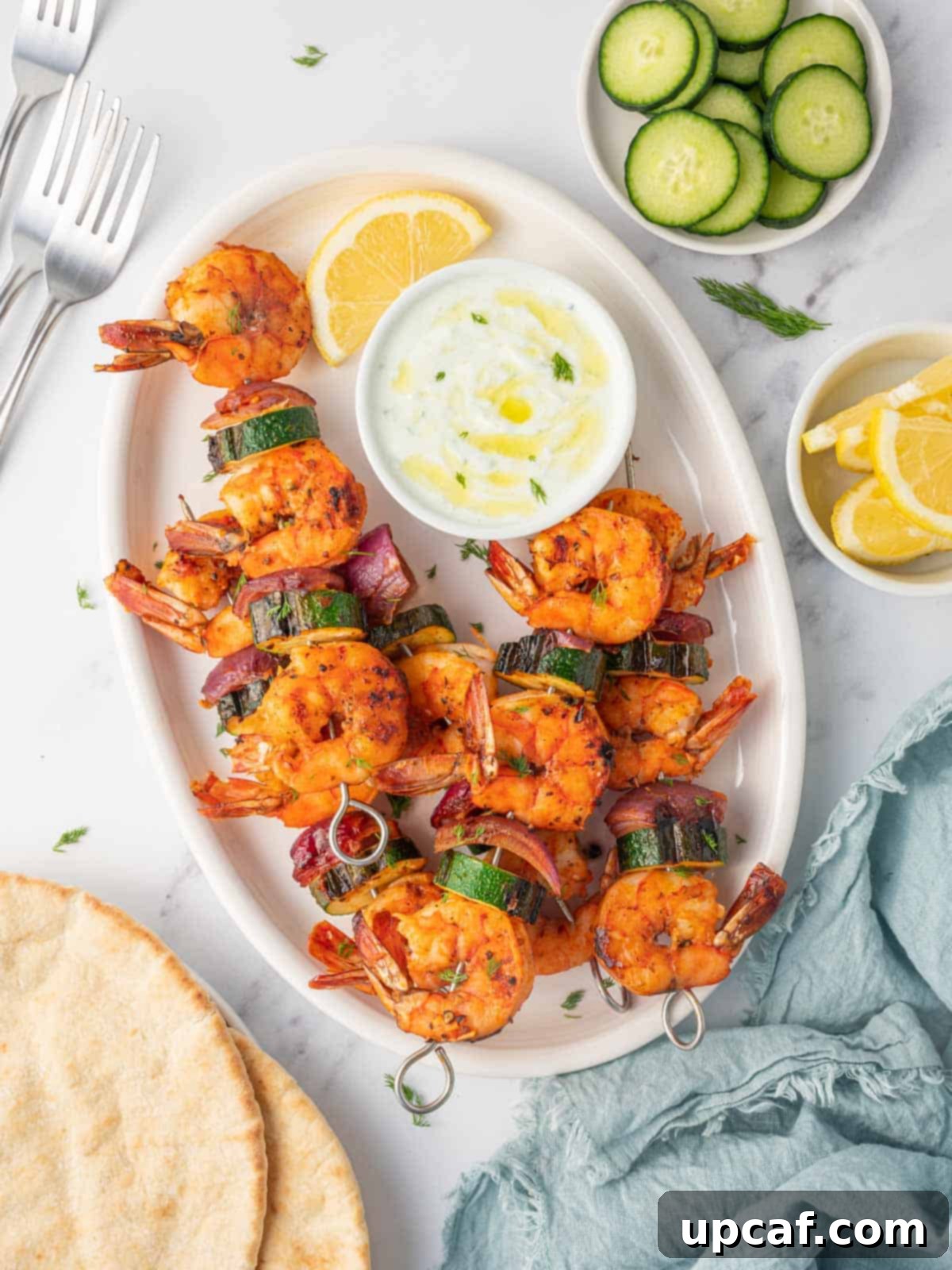 Golden Oven Shrimp Skewers 2 A platter of grilled shrimp with zucchini and onions, garnished with fresh dill and lemon wedges.