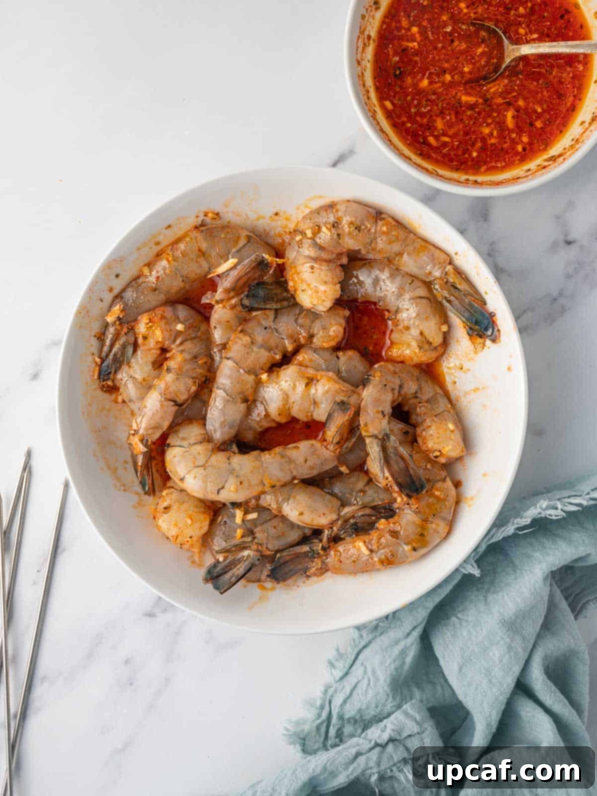 Golden Oven Shrimp Skewers 4 Shrimp marinating in a bowl, coated in a zesty Mediterranean sauce.