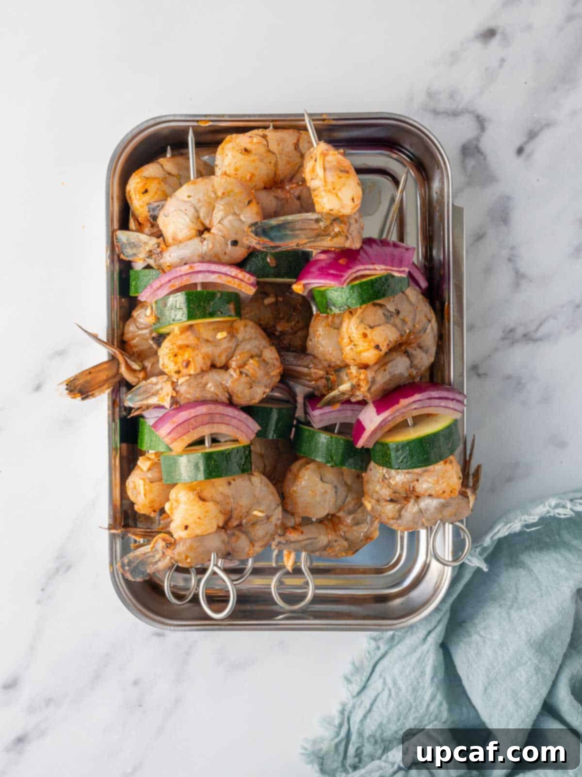 Golden Oven Shrimp Skewers 5 Prepared shrimp skewers ready to be grilled, arranged neatly on a baking sheet.