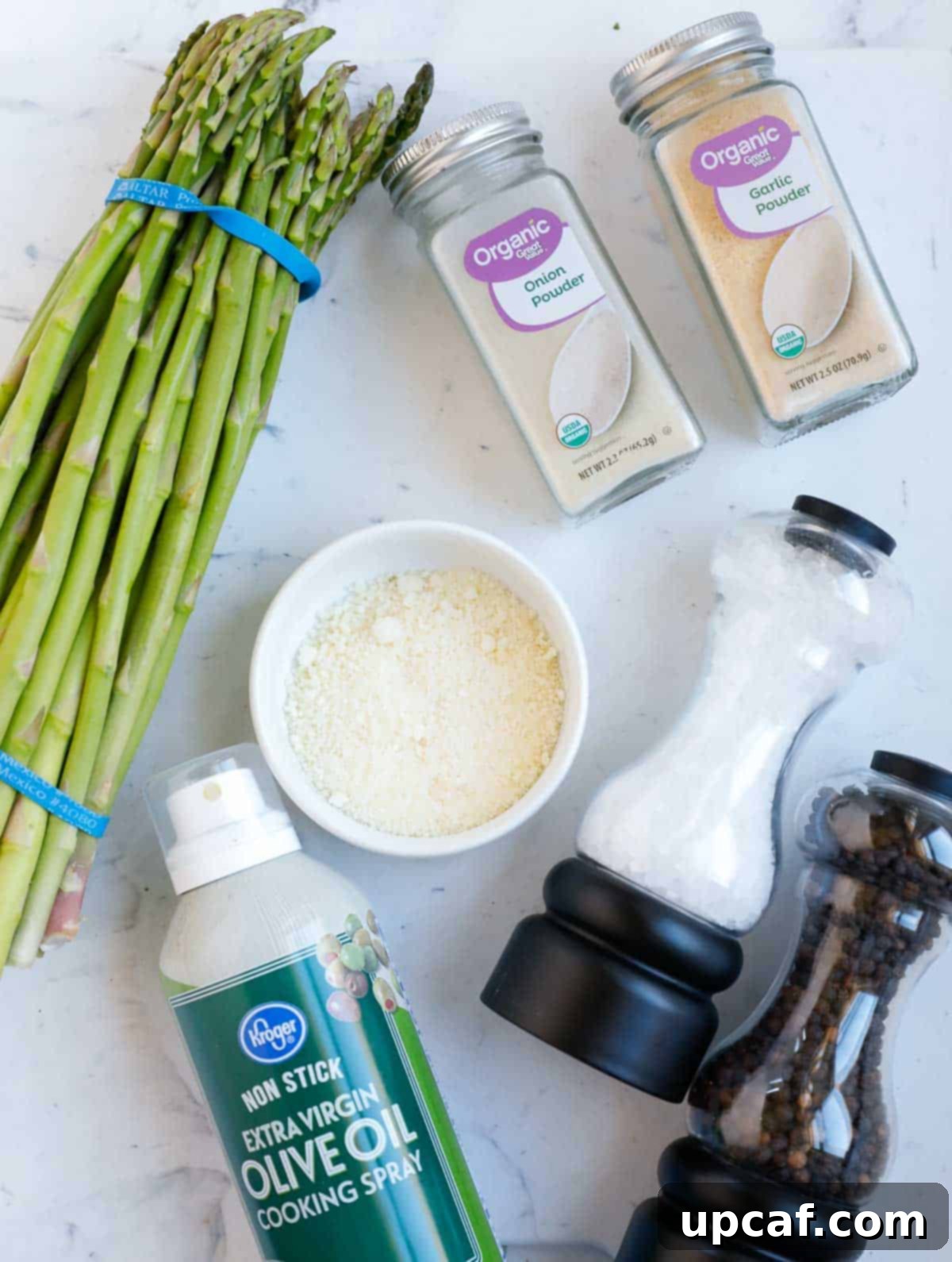 Ingredients needed for air fryer parmesan asparagus, including fresh asparagus, olive oil spray, parmesan cheese, and various seasonings.