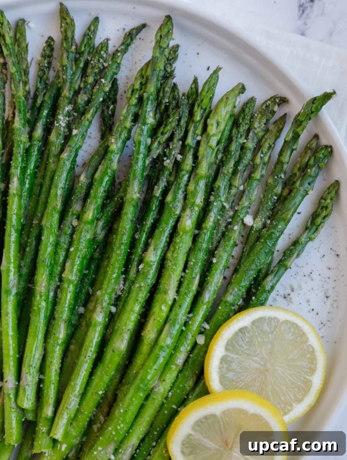 A close-up view of air fryer roasted asparagus, showing its crispy texture and melted Parmesan cheese.