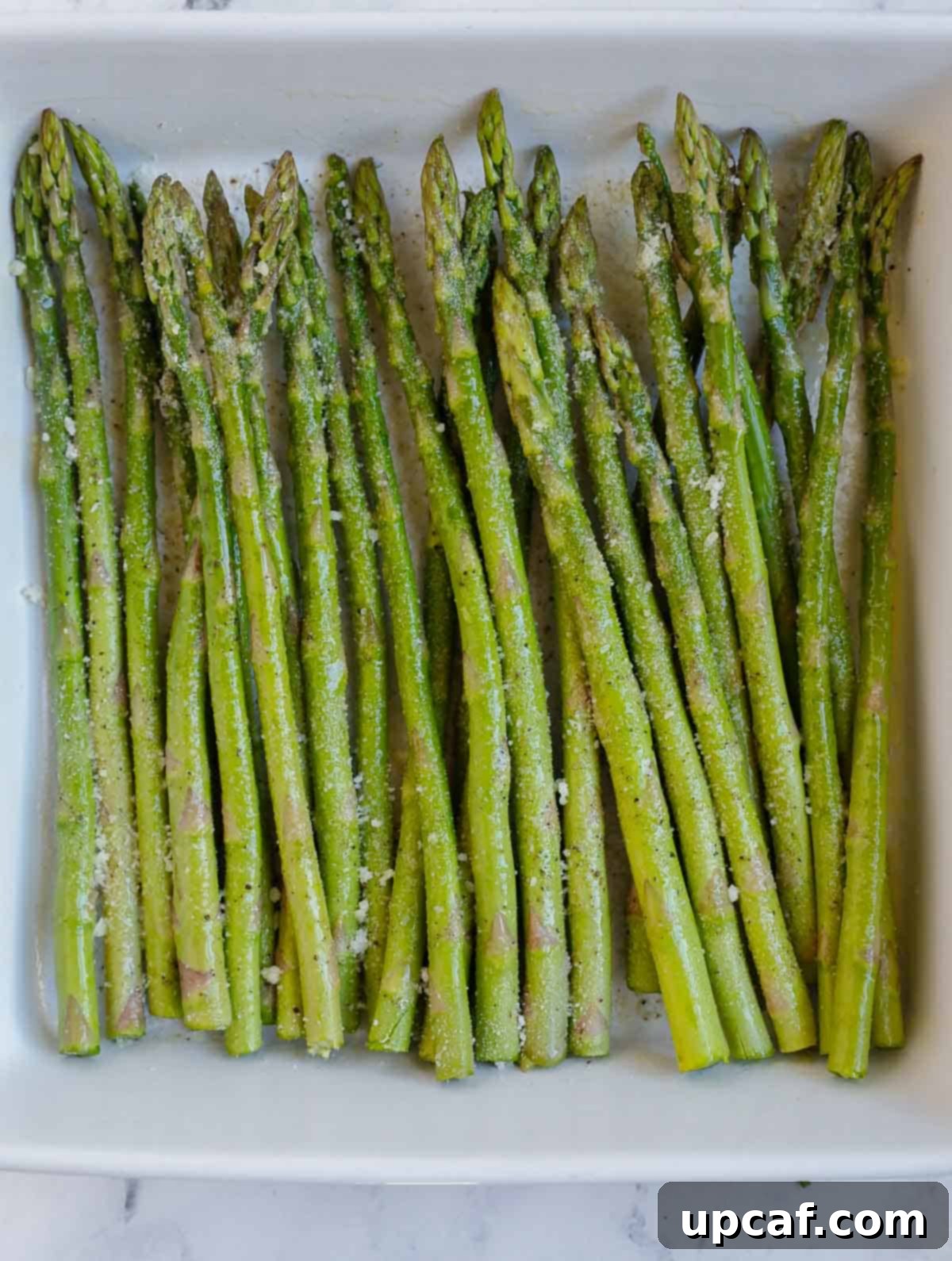 A serving plate with a generous pile of perfectly cooked air fryer parmesan asparagus.