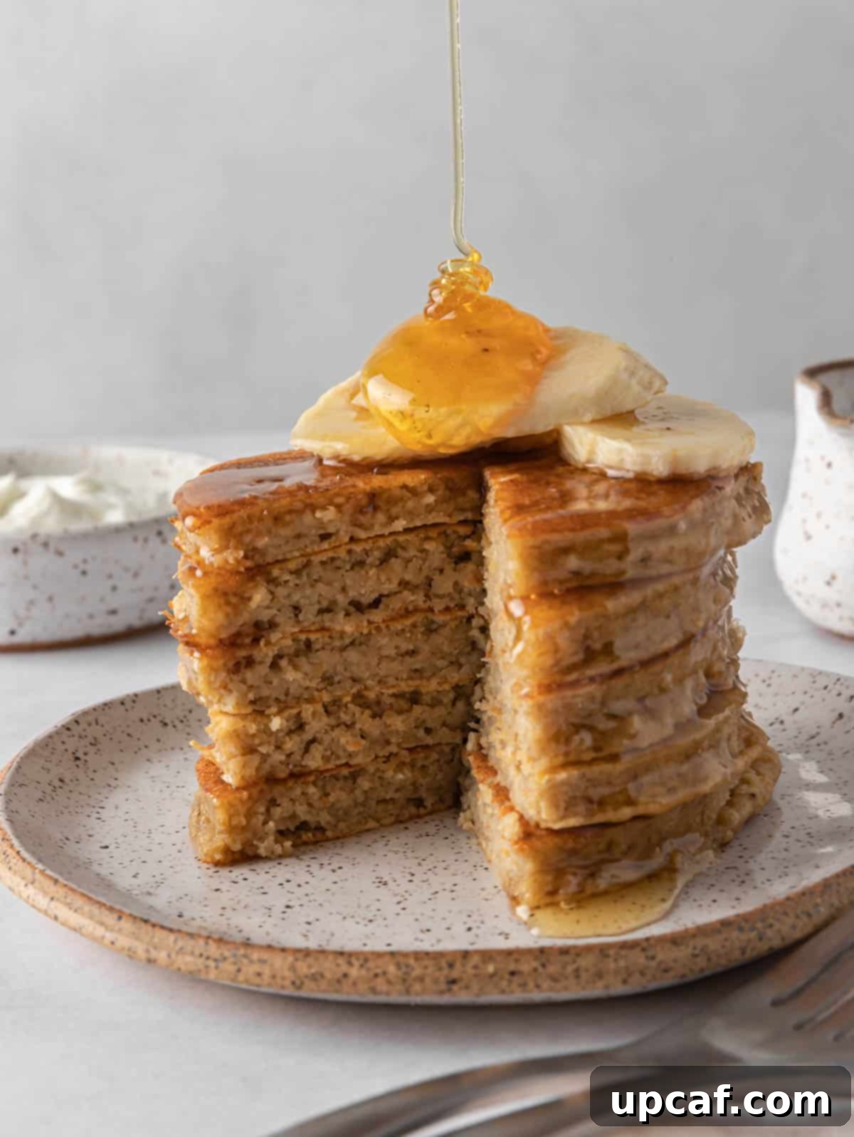 Syrup drizzles onto a stack of protein pancakes.