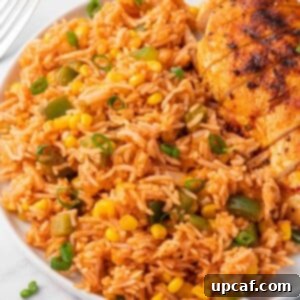 A helping of Mexican fried rice on a plate with grilled chicken.