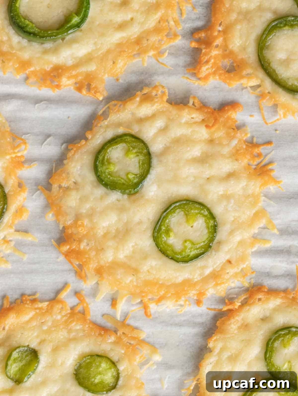 Parmesan chips topped with slices of jalapeno and sprinkled with seasoning, showcased as a delicious, customized snack.