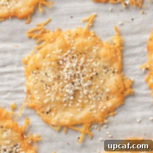 Parmesan cheese chips topped with seasoning on a tray, ready to eat.