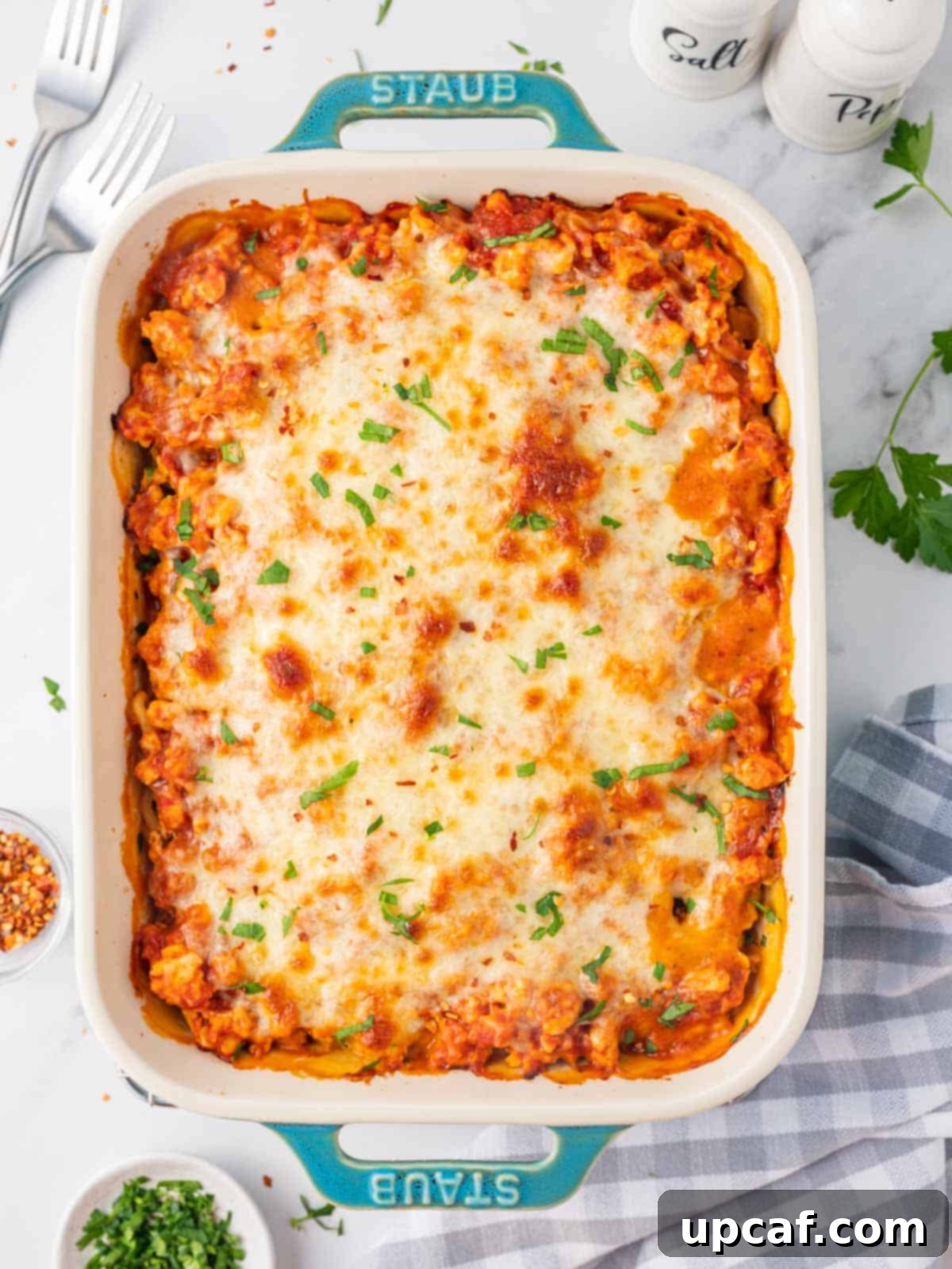 Baked alfredo pasta topped with cheese in a casserole dish, ready to be served.