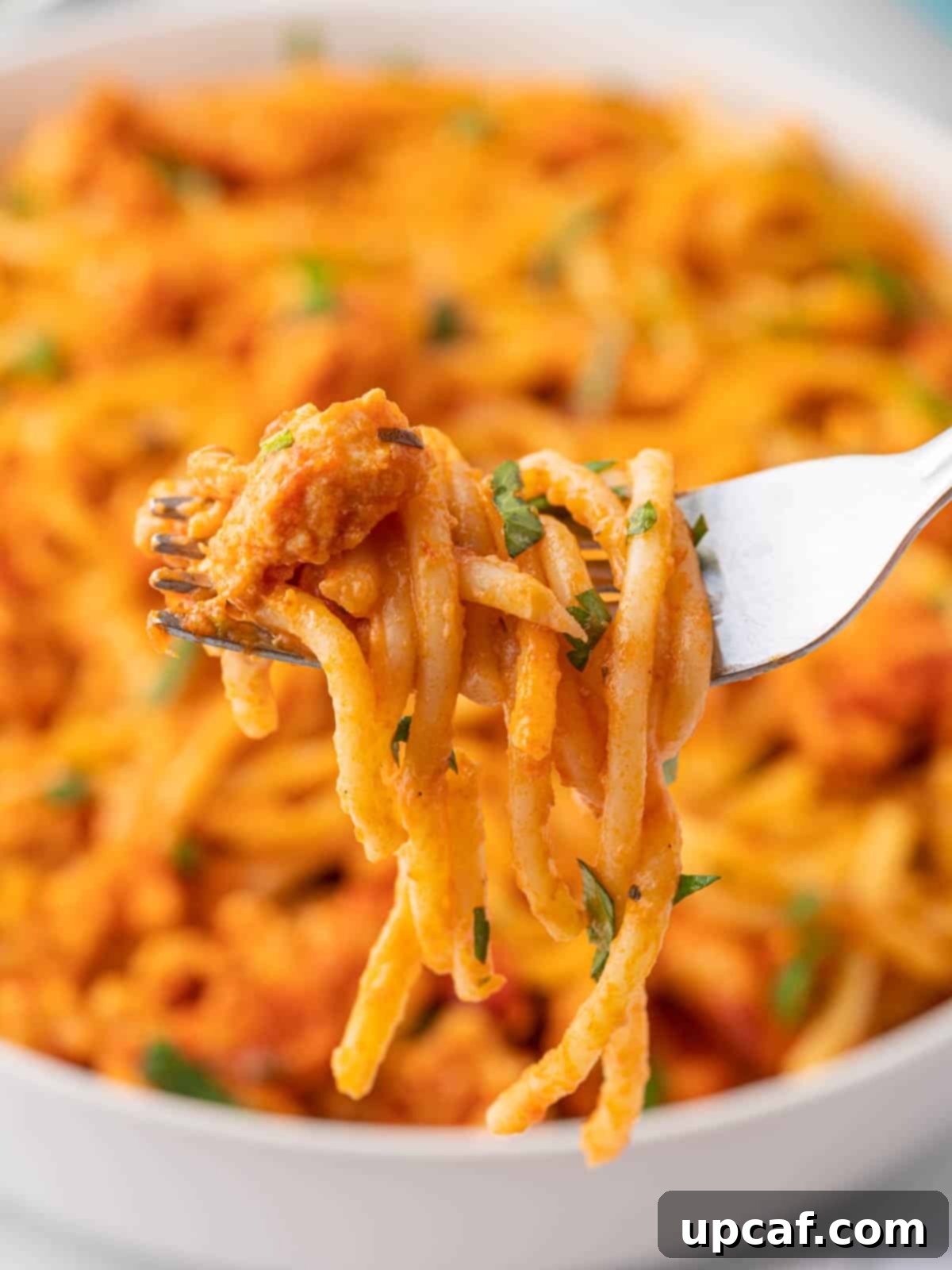 A fork picks up a bite of TikTok Spaghetti, showing the layers of pasta, meat sauce, and melted cheese.