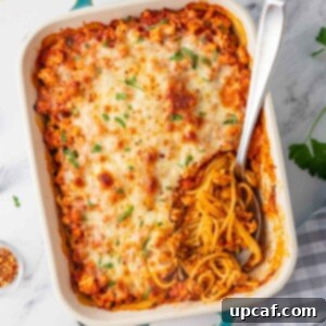 A spoon rests in a casserole dish of million dollar spaghetti.