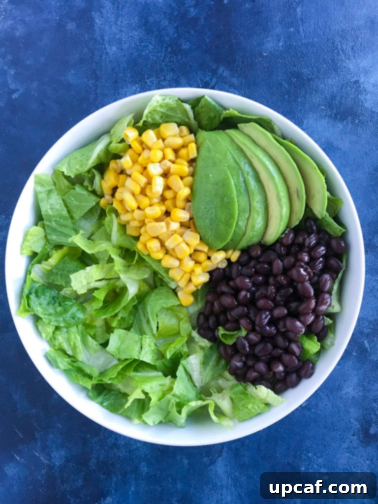 Arranging fresh salad ingredients as the base for the shrimp taco bowl recipe
