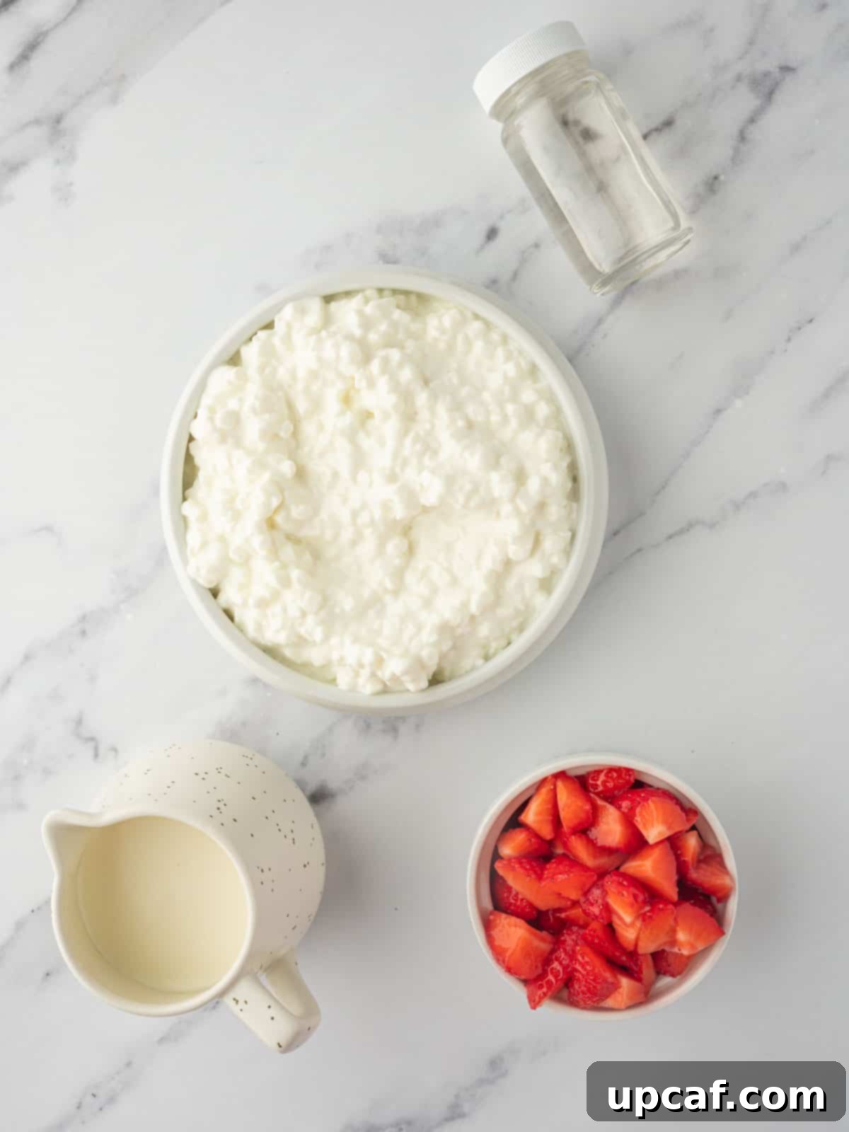 Ingredients needed for strawberry cottage cheese ice cream, including cottage cheese, chopped strawberries, and heavy cream.