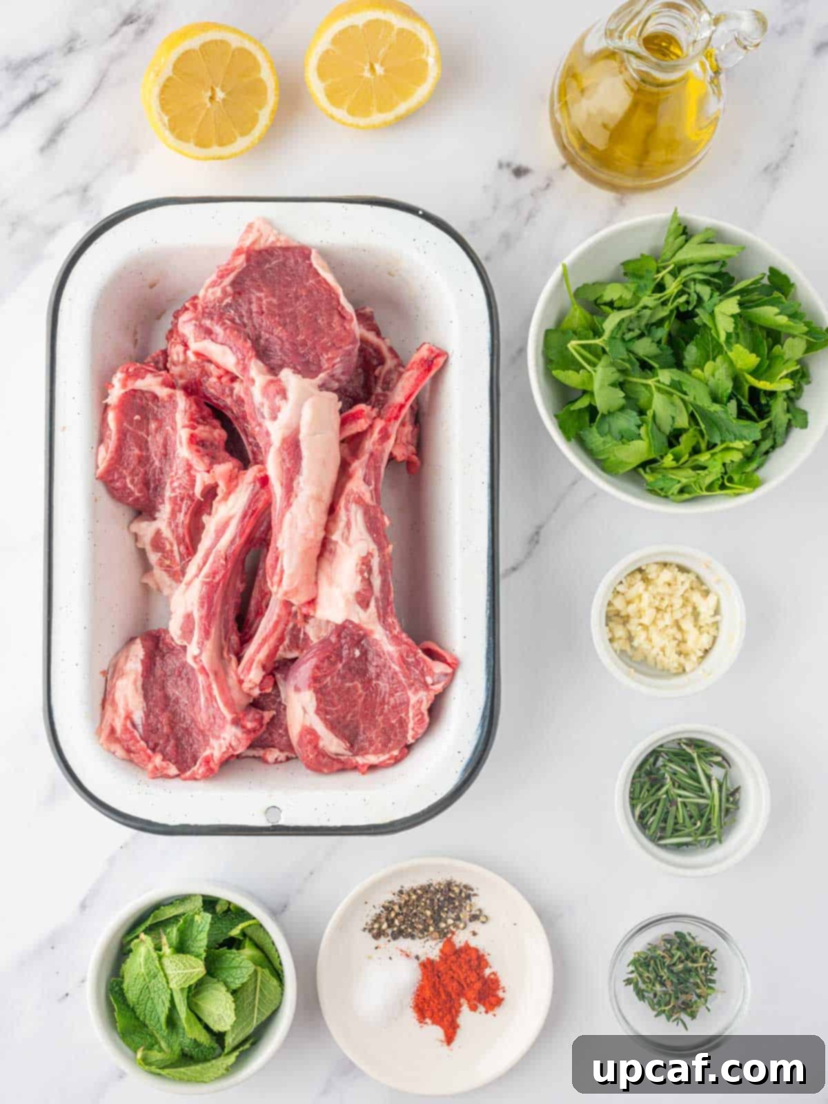 A vibrant selection of ingredients laid out for preparing Mediterranean lamb chops, including fresh herbs, lemons, garlic, and raw lamb chops.