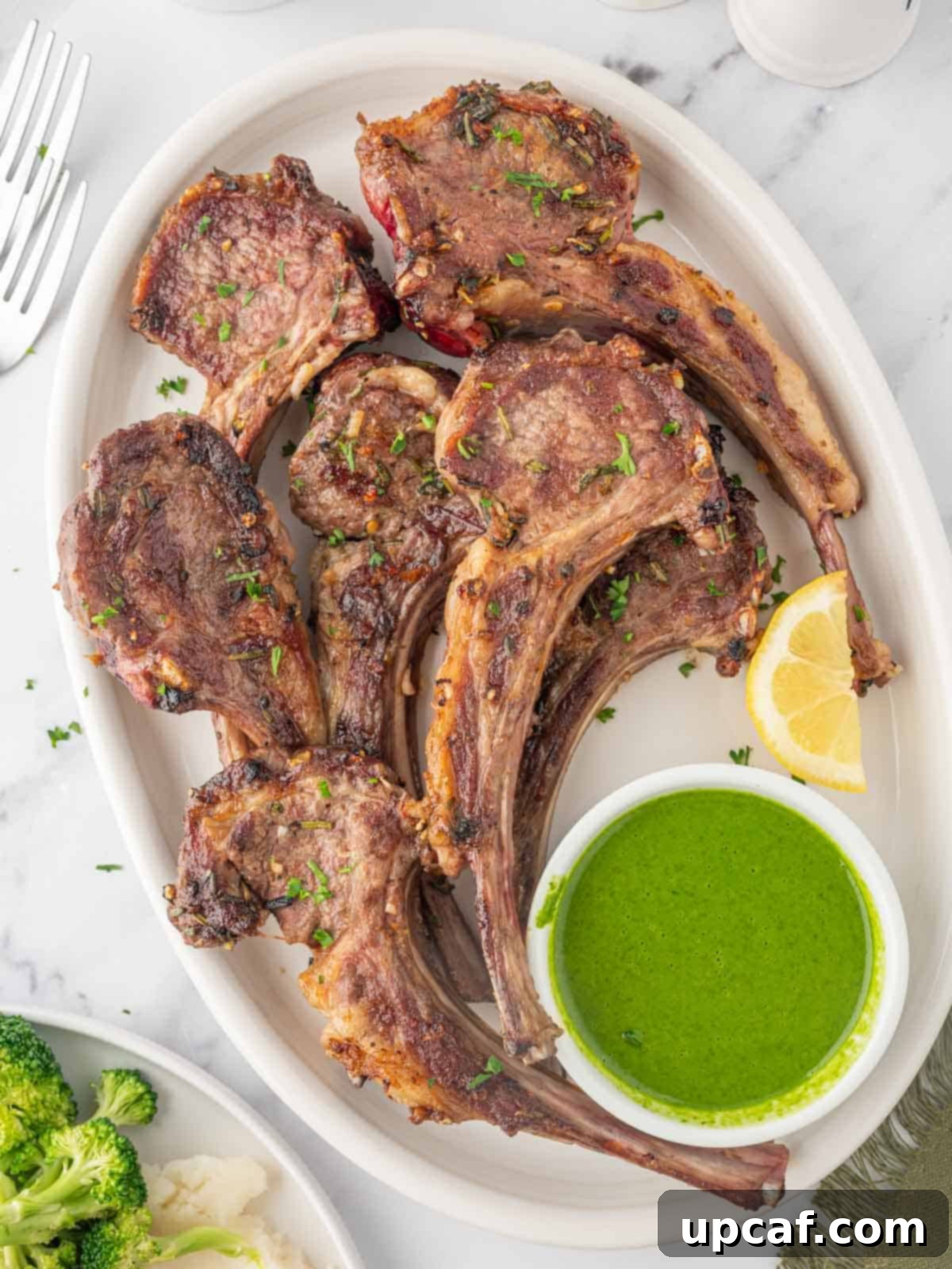 A stunning platter of grilled Mediterranean lamb chops, garnished with fresh herbs and lemon wedges, ready to be served.
