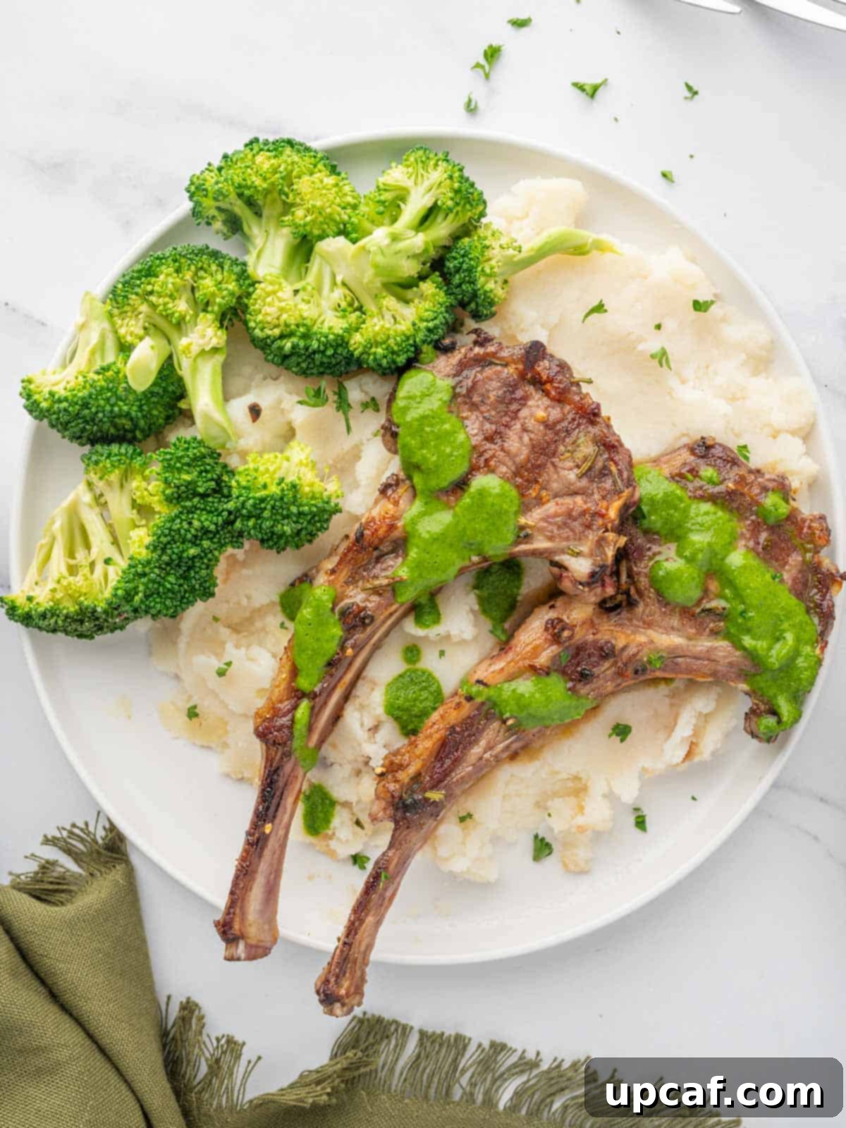 A serving of Mediterranean lamb chops with a side of creamy mashed potatoes and vibrant green broccoli.