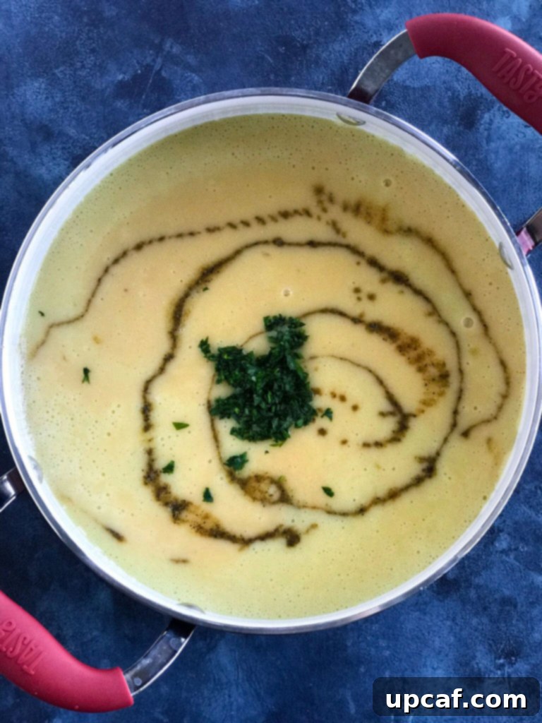 Creamy Lebanese Lentil Soup in a pot, freshly blended, with the vibrant green of added fresh parsley and a hint of steam rising, ready for final seasoning.