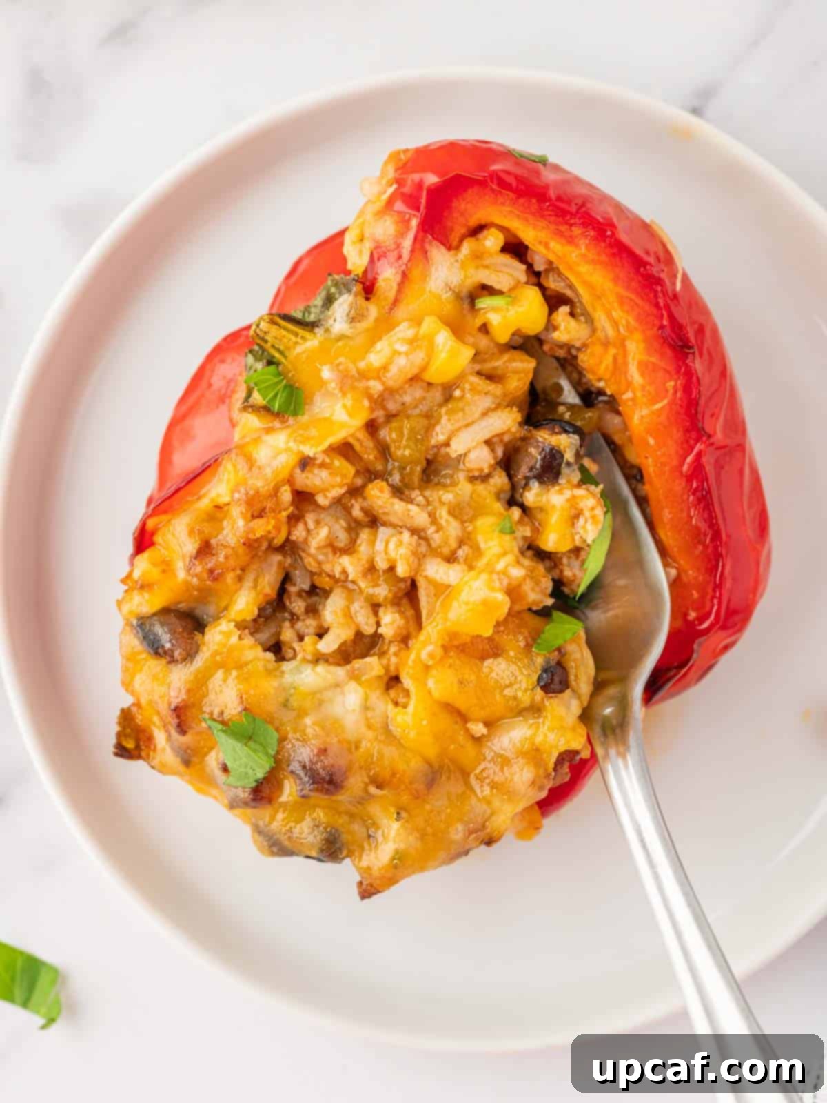 A fork taking a scoop of the rich filling from a perfectly cooked stuffed bell pepper.