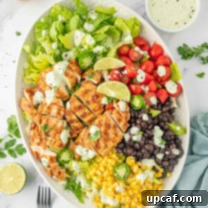 Fiesta Chicken Salad 9 Ingredients for grilled chicken salad recipe piled on a plate with forks and dressing to the side.