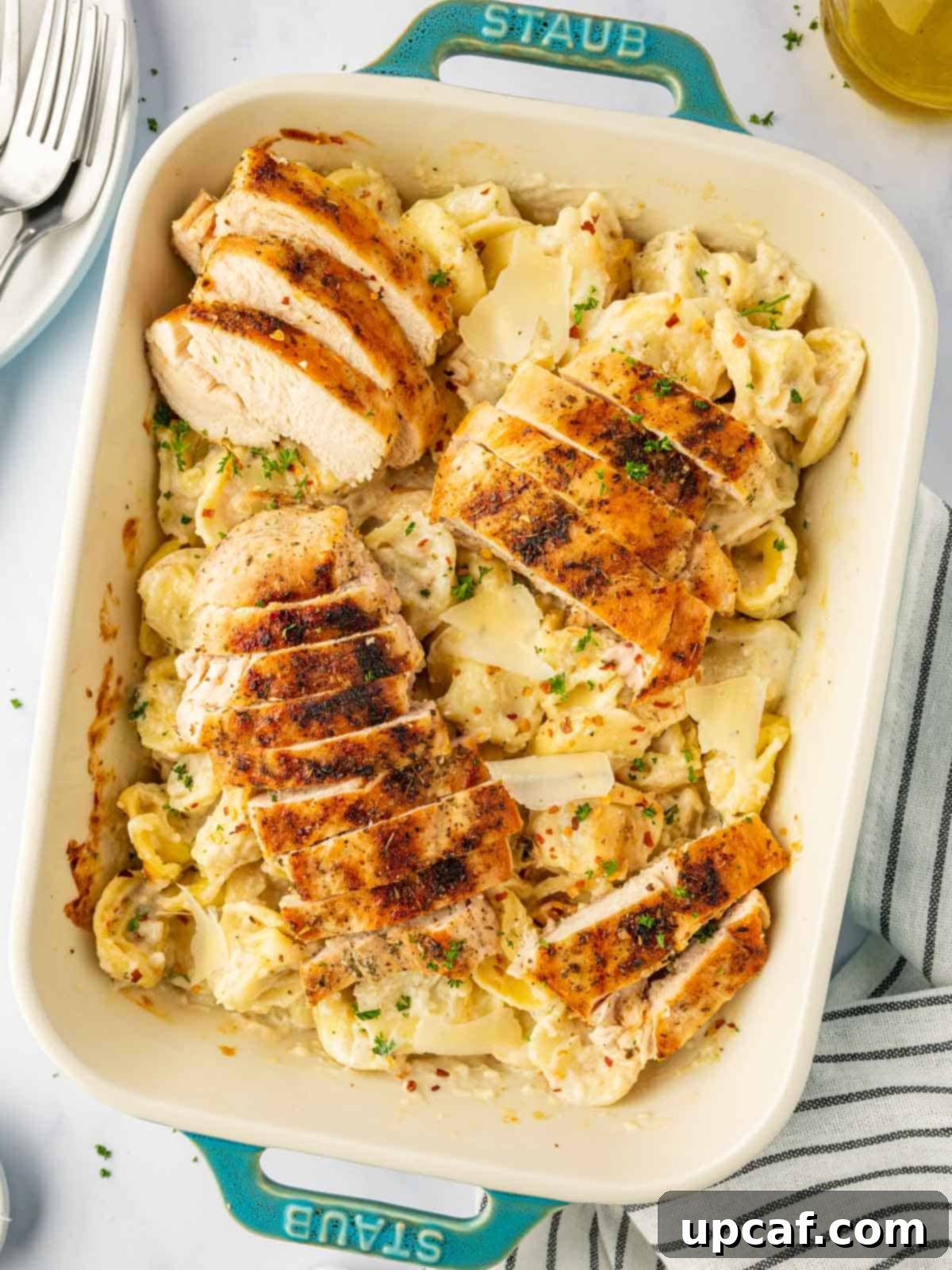 A baking dish with creamy alfredo tortellini and perfectly sliced grilled chicken, ready to be served.