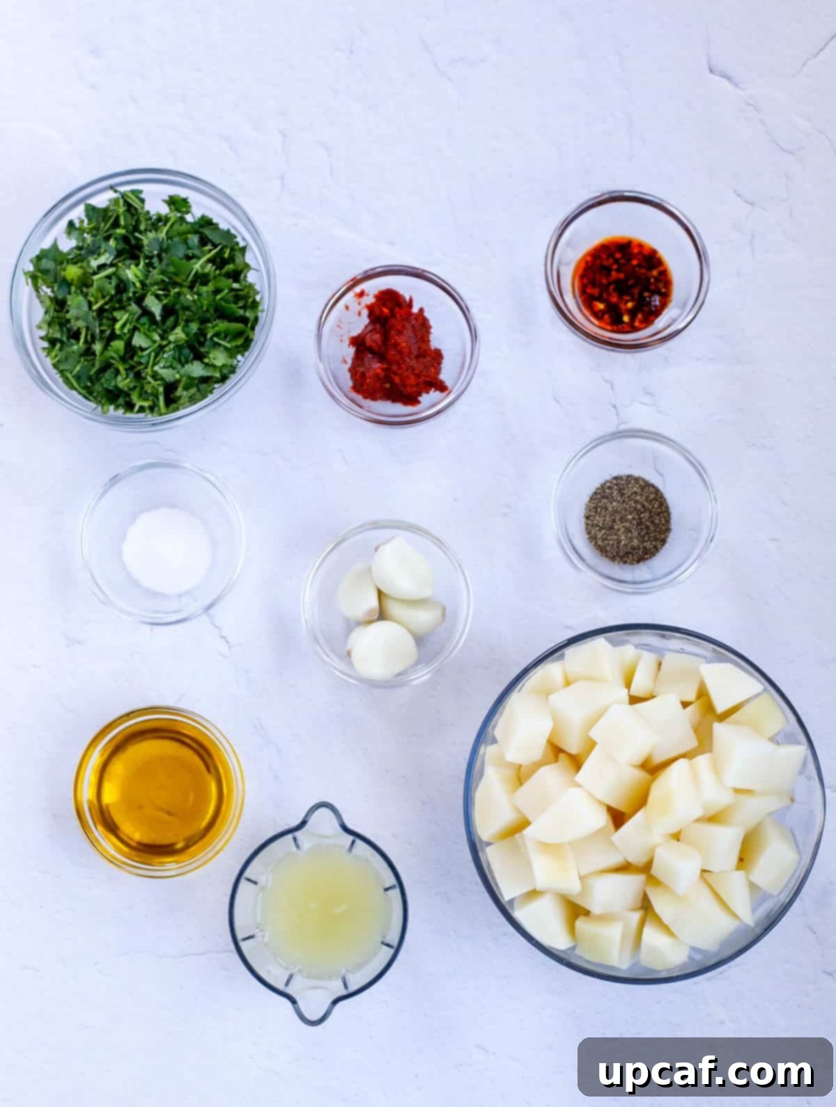 Fresh ingredients laid out for preparing Batata Harra, including potatoes, cilantro, garlic, lemon, and spices.